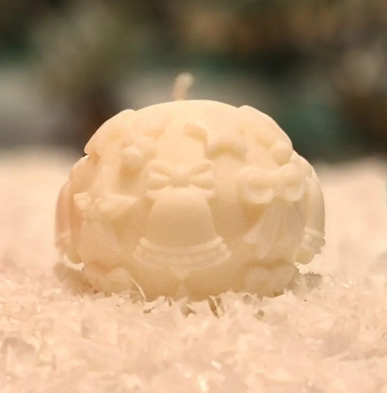 Handmade white soy wax candle Handmade white soy wax candle in a sphere shape with Christmas motifs such as bells, stars and bows