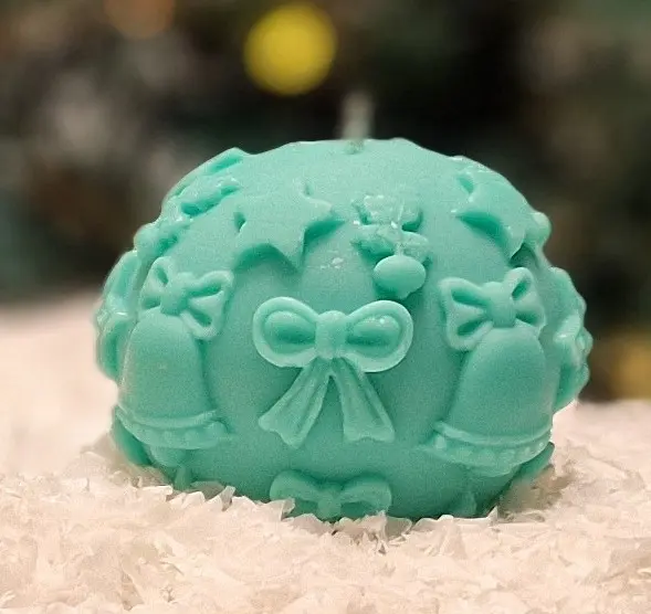 Handmade turquoise soy wax candle Handmade turquoise soy wax candle in a sphere shape with Christmas-themed decorations such as bells, bows and stars