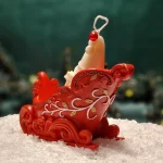 Handgemachte Sojawachskerze mit einem weißen Weihnachtsmann in reich verzierten roten Weihnachtsschlitten.