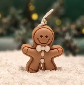 Ręcznie robiona świeca sojowa w kształcie brązowego ludka piernikowego z białymi ozdobami i kokardką