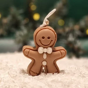 Handgemachte Sojawachskerze in Form eines braunen Lebkuchenmännchens mit weißen Verzierungen und Fliege