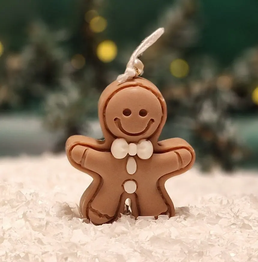 Ręcznie robiona świeca sojowa w kształcie brązowego ludka piernikowego z białymi ozdobami i kokardką Ręcznie robiona świeca sojowa w kształcie brązowego ludka piernikowego z białymi ozdobami i kokardką