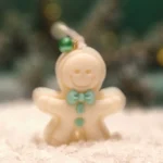 Ręcznie robiona świeca sojowa w kształcie białego ludka piernikowego z miętowymi ozdobami i zieloną perełką na sznurku