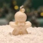 Ręcznie robiona świeca sojowa w kształcie białego ludka piernikowego, ozdobiona perełką na sznurku