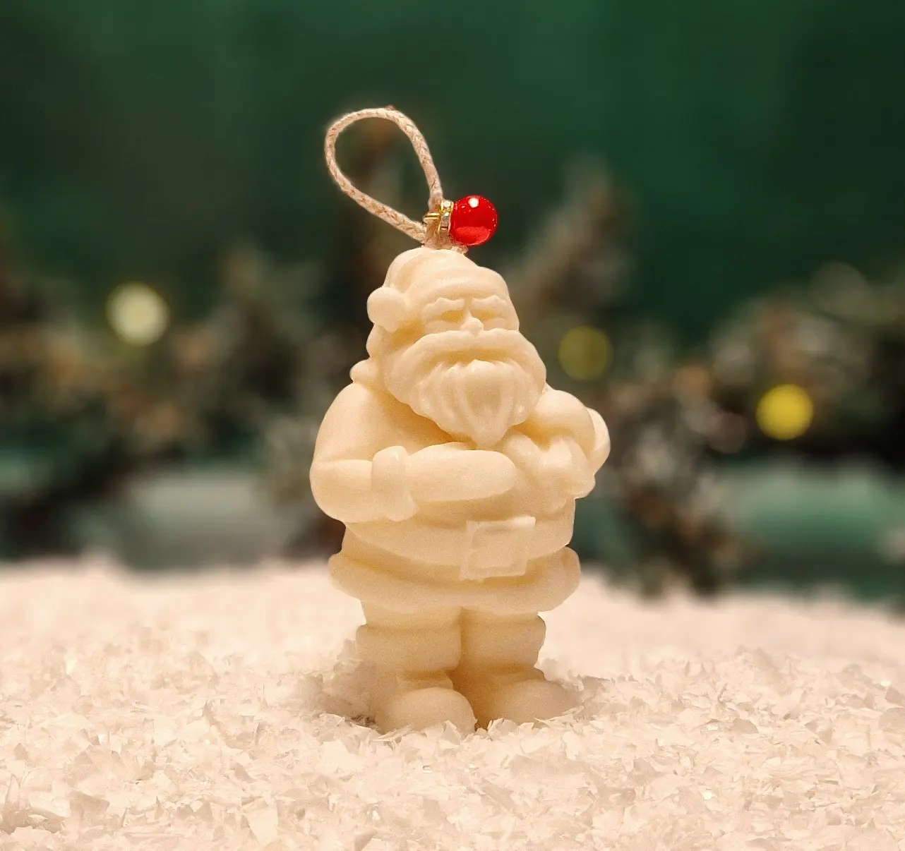 Ręcznie robiona świeca sojowa w kształcie białego Mikołaja, ozdobiona czerwonym koralikiem na sznurku