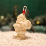 Ręcznie robiona świeca sojowa w kształcie białego Mikołaja, ozdobiona czerwonym koralikiem na sznurku