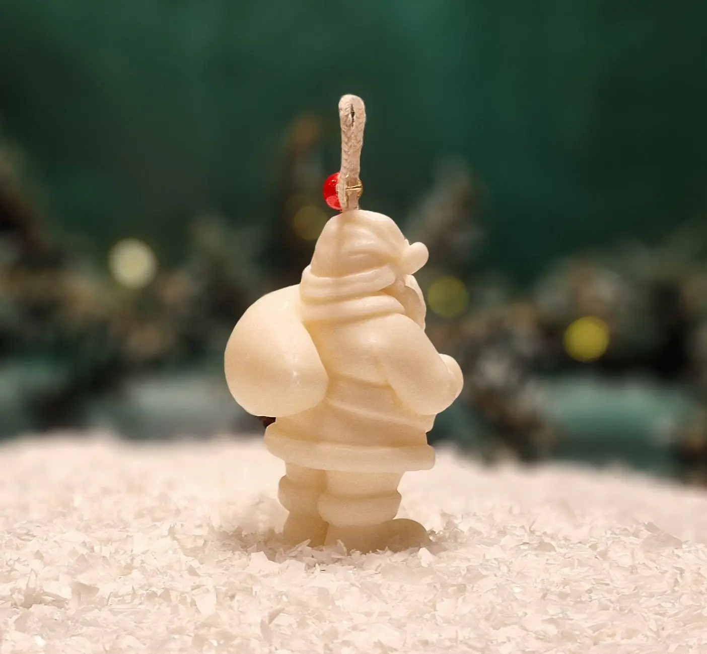 Ręcznie robiona świeca sojowa w kształcie białego Mikołaja, ozdobiona czerwonym koralikiem na sznurku