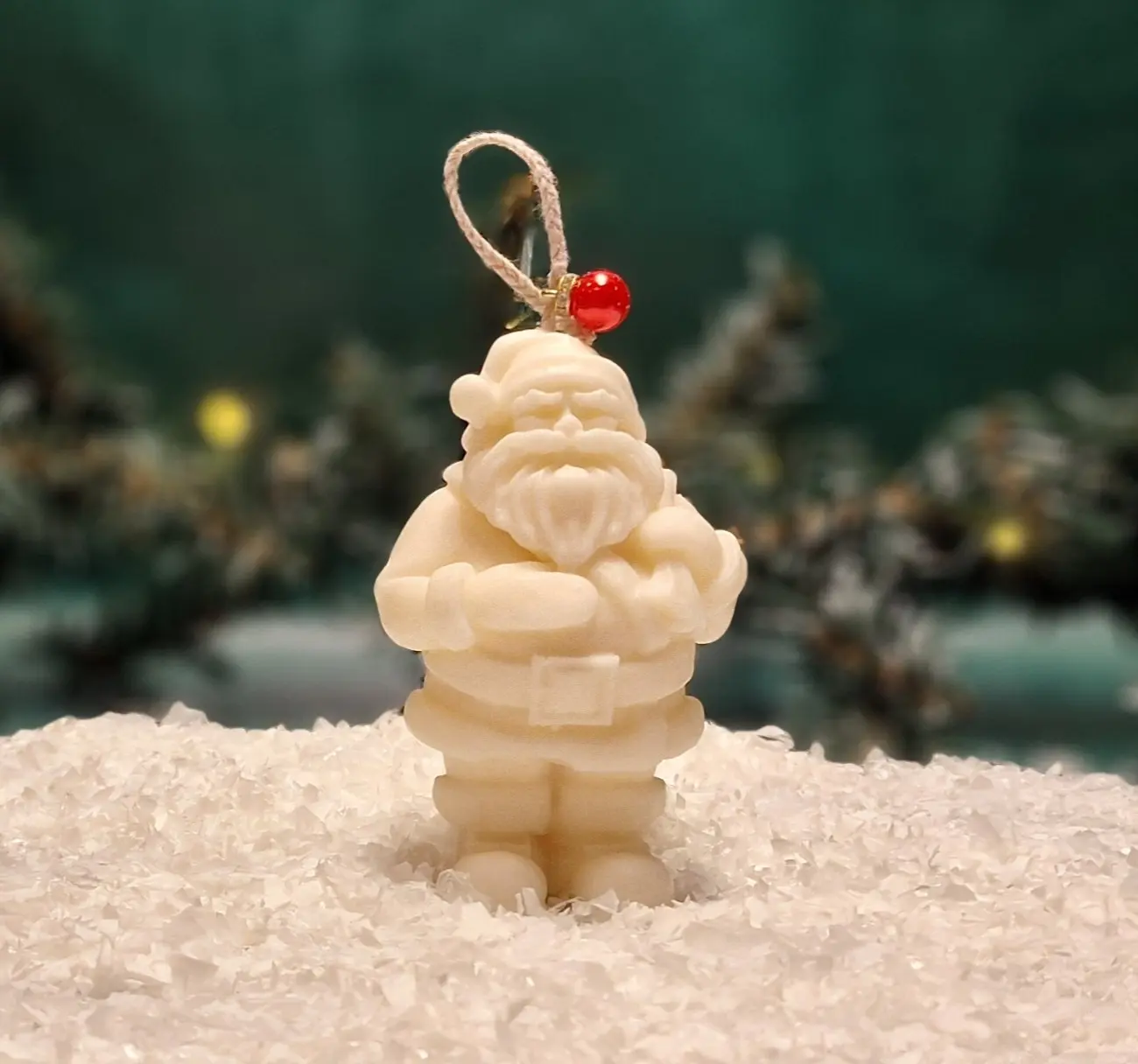 Ręcznie robiona świeca sojowa w kształcie białego Mikołaja, ozdobiona czerwonym koralikiem na sznurku