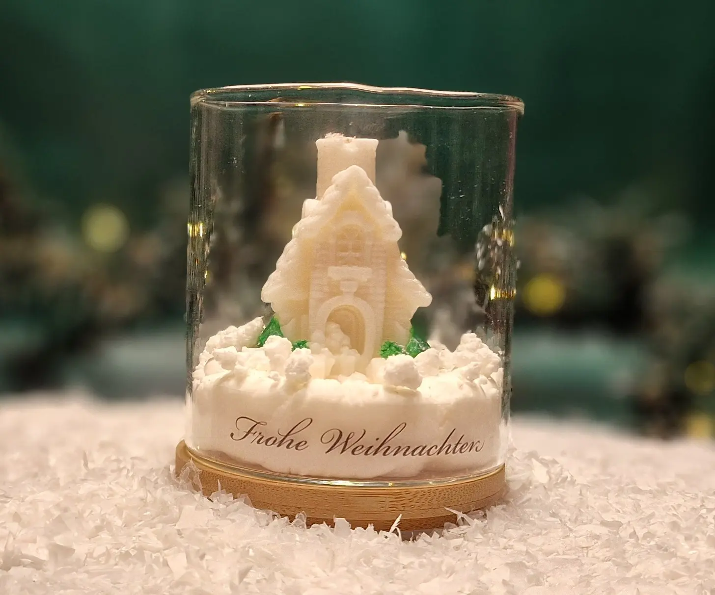 Handmade soy wax candle shaped like a snowy cottage with trees, displayed in a glass jar with a wooden base and the inscription ‘Frohe Weihnachten’. Handmade soy wax candle shaped like a snowy cottage with trees, displayed in a glass jar with a wooden base and the inscription ‘Frohe Weihnachten’.