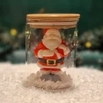 Handgemachte Sojawachskerze in Form eines Weihnachtsmanns in einem Glas mit Holzdeckel und dem Schriftzug ‘Frohe Weihnachten’