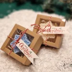 Ręcznie robione świąteczne świeczki sojowe w kształcie płatków śniegu, zapakowane w ekologiczne pudełka z etykietą ‘Merry Christmas’