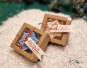 Ręcznie robione świąteczne świeczki sojowe w kształcie płatków śniegu, zapakowane w ekologiczne pudełka z etykietą ‘Merry Christmas’