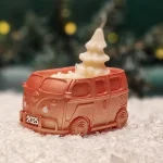 Handgemachte kupferfarbene Sojawachskerze in Form eines 2025-Busses mit einem weißen Tannenbaum als Docht