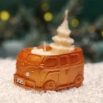 Handgemachte goldfarbene Sojawachskerze in Form eines 2025-Busses mit einem weißen Tannenbaum als Docht