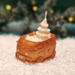 Handgemachte goldfarbene Sojawachskerze in Form eines 2025-Busses mit einem weißen Tannenbaum als Docht