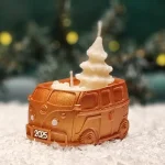 Handgemachte goldfarbene Sojawachskerze in Form eines 2025-Busses mit einem weißen Tannenbaum als Docht