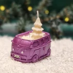 Handgemachte lilafarbene Sojawachskerze in Form eines 2025-Busses mit einem weißen Tannenbaum als Docht