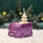 Handgemachte lilafarbene Sojawachskerze in Form eines 2025-Busses mit einem weißen Tannenbaum als Docht