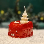 Handgemachte rote Sojawachskerze in Form eines 2025-Busses mit einem weißen Tannenbaum als Docht